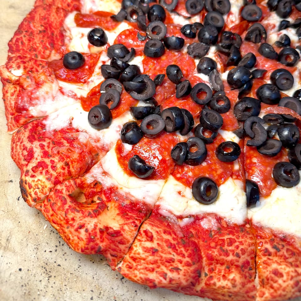 Close-up of a pepperoni and black olive pizza, sliced and ready to eat.