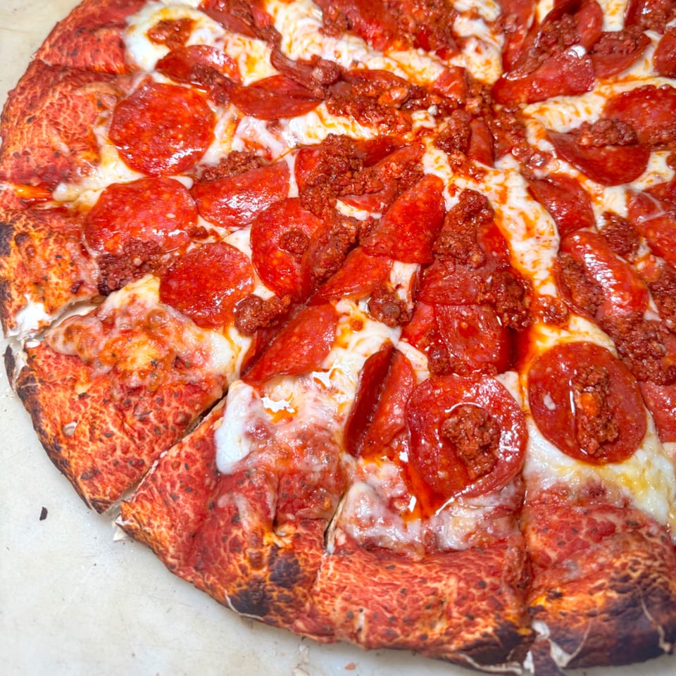 Close-up of a pepperoni and sausage pizza with melted cheese and a crispy crust.