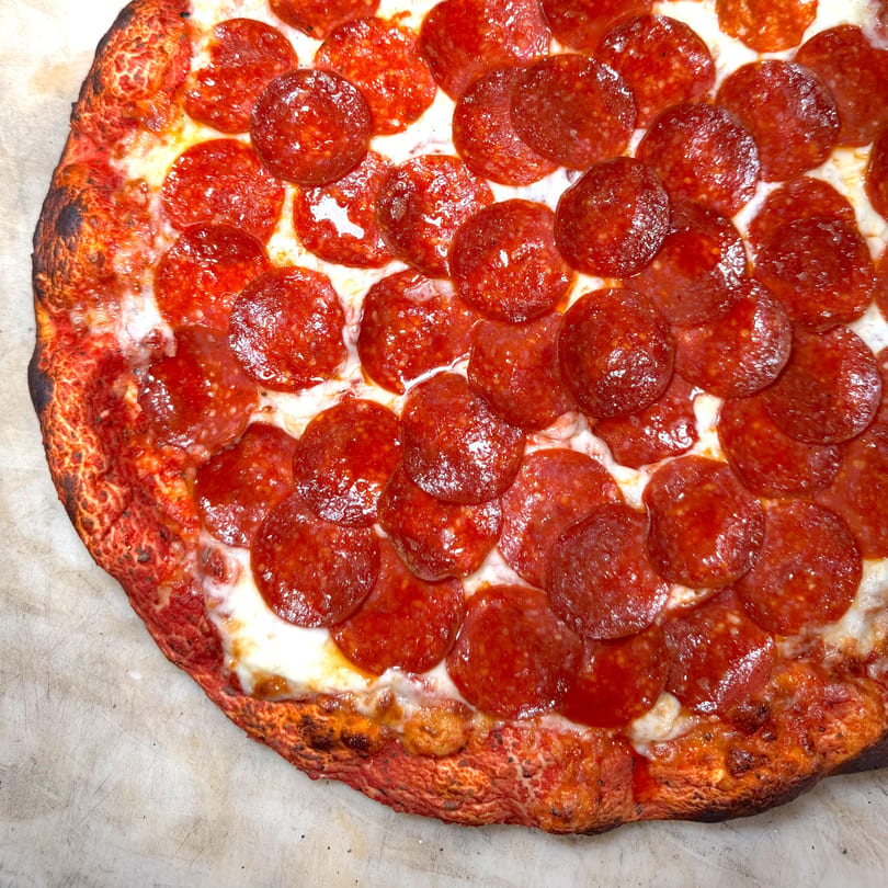 Close-up of a freshly baked pepperoni pizza with a crispy crust and melted cheese.