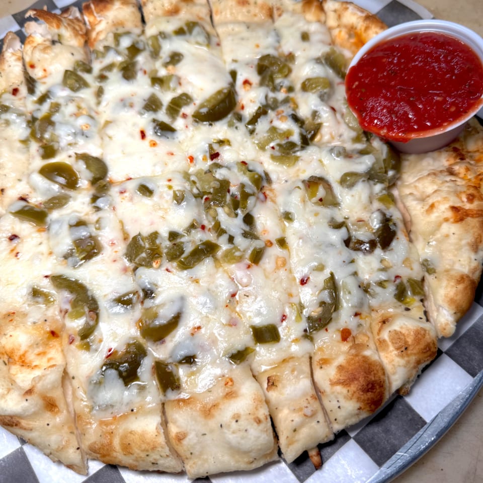 Cheesy breadsticks with green peppers and red pepper flakes, served with a side of marinara sauce.